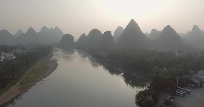 Aerial shot of passenger boats,rafts in beautiful Li River surrounded by karst mountains at sunset or sunrise in Yangshuo,Guilin,China. Travel, picturesque famous destination and adventure concept.