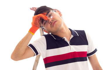 Young man holding electric screwdriver and sitting on ledder