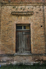 Fototapeta na wymiar Vieja puerta de madera en pared de ladrillos
