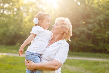 Grandmother hugging granddaughter legs and smiling.