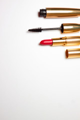 Red open lipstick, black mascara for eyes on a white background. view from above. Fashionable women's cosmetics