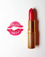 red lipstick in golden tube and lip print on a white background