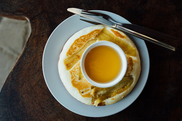 Baban cake lies on round white plate on wooden table. Banana pancake on plate