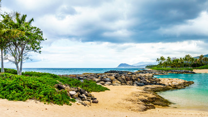 Palm trees in the wind and the Ko Olina Lagoon under cloudy sky at the resort community of Ko Olina on the West Coast of the Hawaiian island of Oahu  © hpbfotos