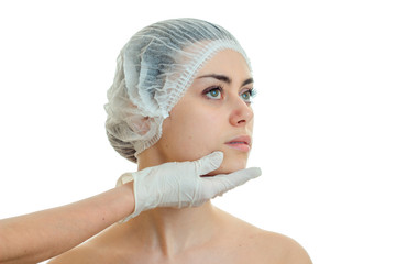 Portrait of a young girl who turned her head in a medical hat and doctor glove touches her face