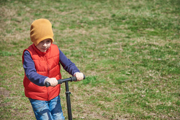 Cute European boy skating a scooter.