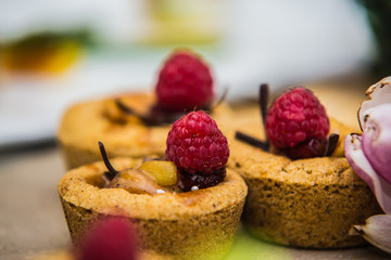 cupcakes decorated with fresh cream and raspberries.