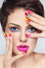 Young beautiful girl with fancy make-up and colorful french manicure