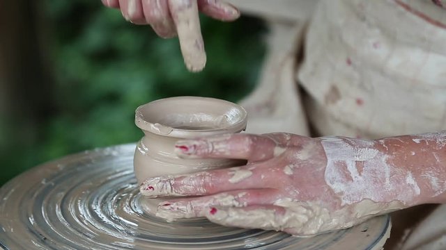 Man and woman makes a pot on pottery wheel. Hands of a potter and his apprentice. Man and woman hands