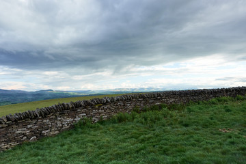 Fototapeta na wymiar old dry stone wall in welsh countryside, mountains in background
