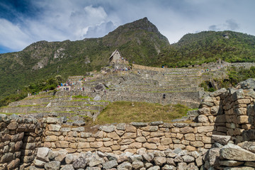 Fototapeta na wymiar MACHU PICCHU, PERU - MAY 18, 2015: Tourists and a building called guardhouse at Machu Picchu ruins, Peru.