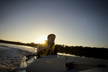 Young boy diving a boat in the ocean.
