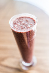 Macro closeup of red fruit smoothie in glass with bubbles