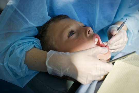 Boy getting teeth examined by the dentist