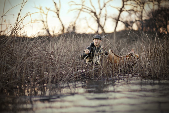 Young adult man duck shooting with a gun and a canoe in a lake.