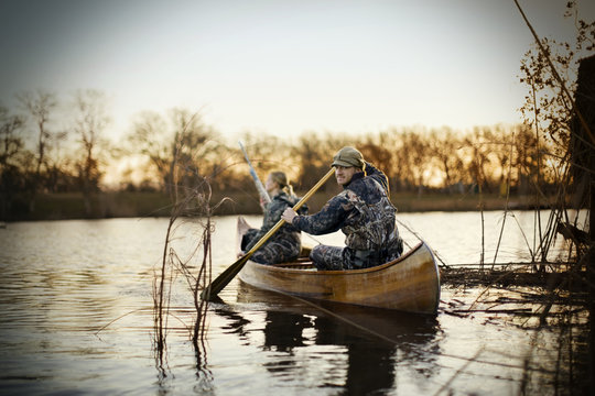 Couple in camouflage attire riding canoe in lake