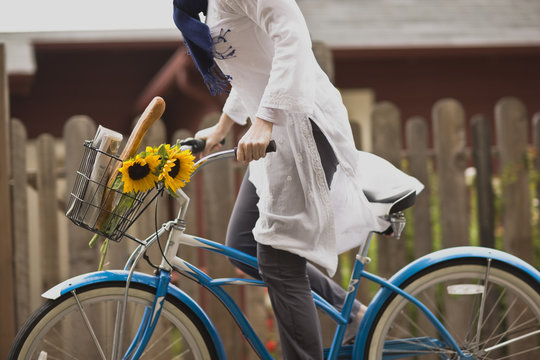 Woman riding a bicycle with sunflowers in the basket