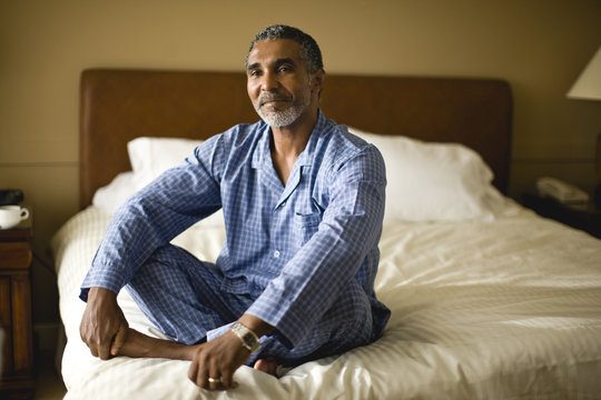 Man sitting cross legged on a bed.