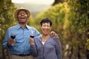 Happy senior couple drinking red wine in the vineyard