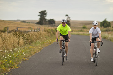 Portrait of a happy mature couple cycling along a country road.