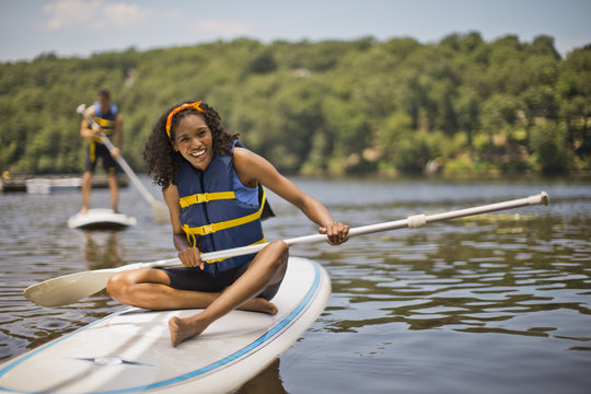 Portrait of a smiling young woman sitting on a paddleboard.