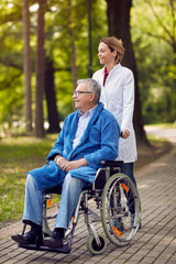 portrait of elderly man on wheelchair with nurse outdoor.