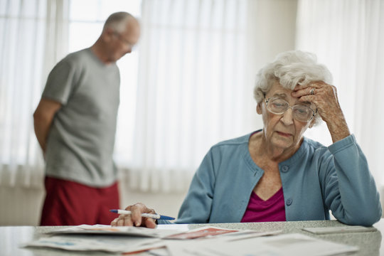 Anxious elderly couple worry about how they will pay all the bills they have received.