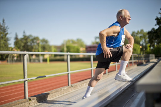 Senior man stretching before a race at a sports track.