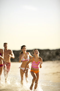 Family running together on a beach.