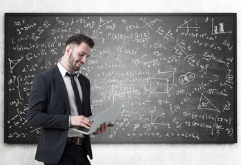 Man with laptop and blackboard with formulas