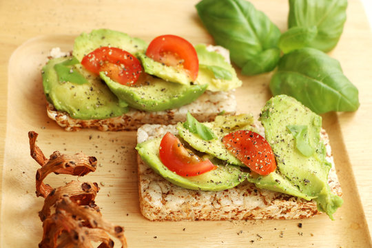 Kanapee with avacado and basil on the wooden plate
