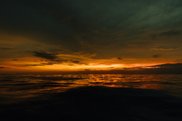 Fototapeta na wymiar Gloomy sunset in evening sea. Beautiful sunset in cloudy sky on ocean