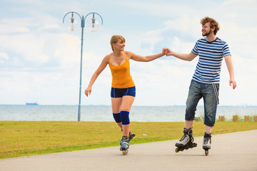Obraz premium Young couple on roller skates riding outdoors