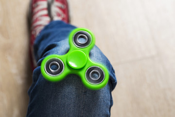 Little girl playing with green fidget spinner toy