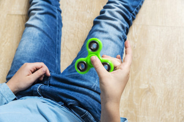 Little girl playing with green fidget spinner toy