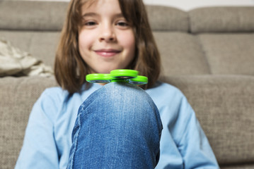 Little girl playing with green fidget spinner toy