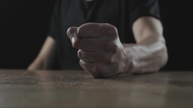 Fist of angry man beats on the table in slow motion