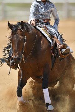 A front view of a rider sliding the horse in the dirt
