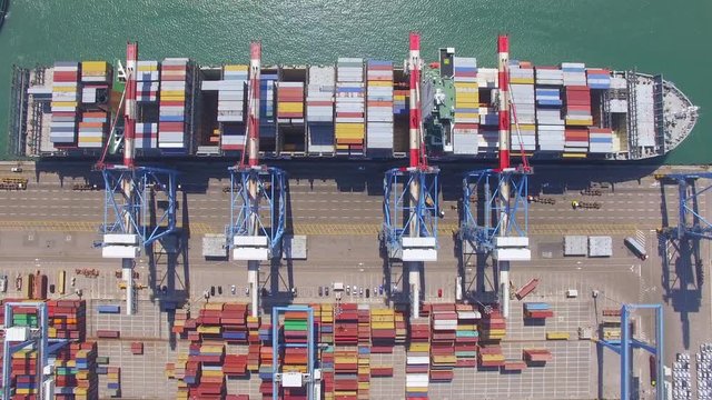 Aerial Time lapse - Commercial port with container ship during loading and unloading - Top down view.