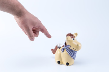 Caucasian hand pointing a country horse piggy saving bank moneybox with a coin on its back hole
