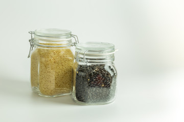 Rice and beans dry and raw in glass jars isolated on white background