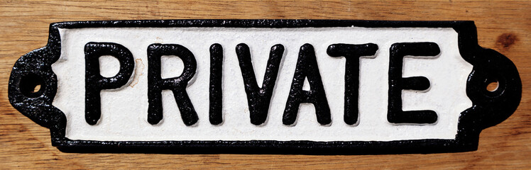 Sign with the word private written on it in black and white, on a wooden background. 
