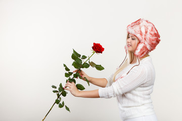 Woman in winter furry hat holding red rose