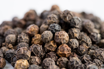 Black pepper seeds on a white background with some blurry effects (bokeh) applied. Organic seeds origin from Sarawak of Borneo, Malaysia.