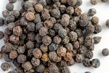 Black pepper seeds on a white background with some blurry effects (bokeh) applied. Organic seeds origin from Sarawak of Borneo, Malaysia.