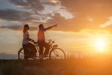Fototapeta premium silhouette of sweet young couple in love happy time on bicycle