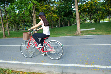 Young asian beautiful woman on bike in green road