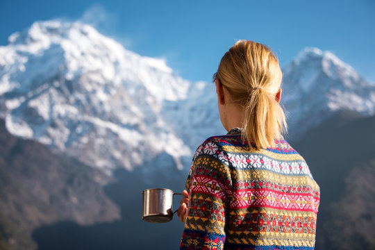 Fototapeta Turystka z kubkiem w ręku podziwiająca ośnieżone góry.