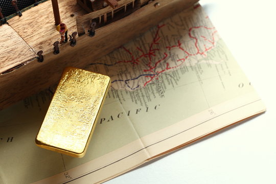 Miniature scratch build junk ship wooden model and gold bar put on the old paper map.