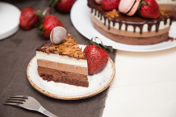 Three chocolate cake decorated with strawberries and macaroons